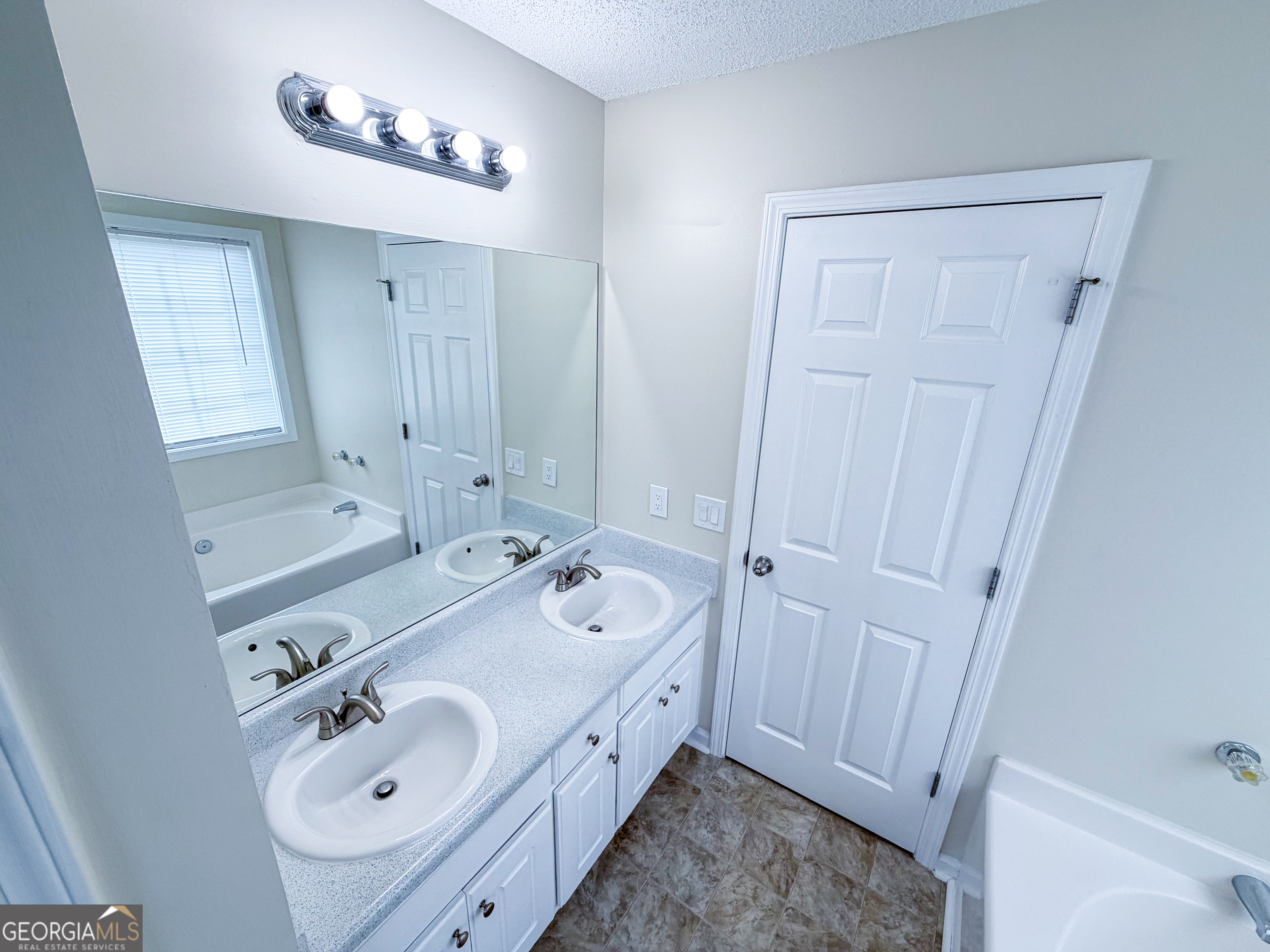 1119 Hummingbird Way Winder, GA 30680 - Photo 23 of 38 a spacious bathroom with 2 sink tub and a mirror