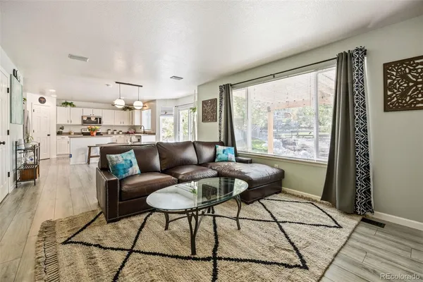 a living room with stainless steel appliances granite countertop furniture a rug a counter and a large window