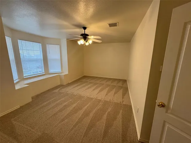 a view of empty room with chandelier fan and window