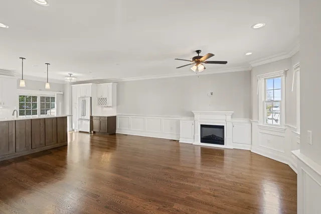 a view of a livingroom with a fireplace a ceiling fan and windows