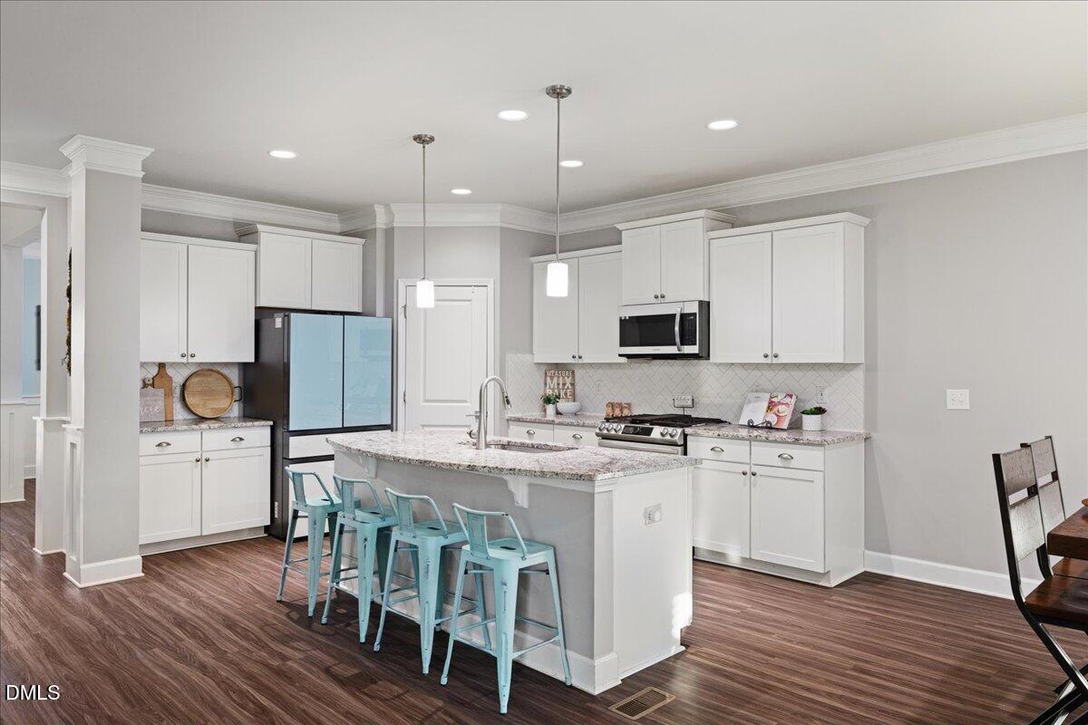 7804 Charters End Street Willow Spring, NC 27592 - Photo 6 of 43 a kitchen with stainless steel appliances granite countertop a table chairs sink refrigerator and microwave