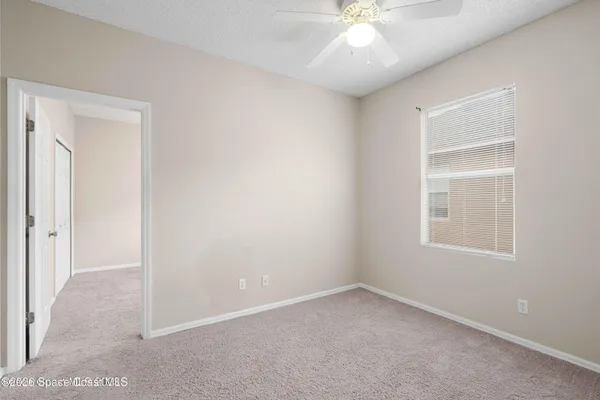an empty room with a window and a fan