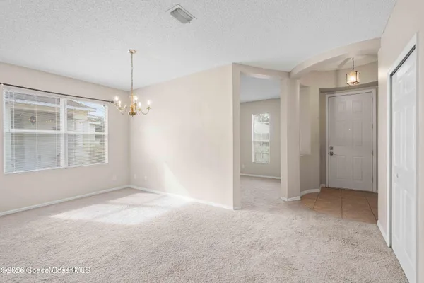 a view of empty room with windows and chandelier fan