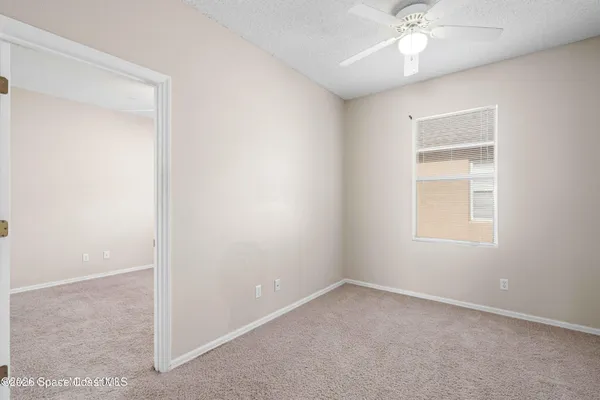 an empty room with a window and a chandelier fan