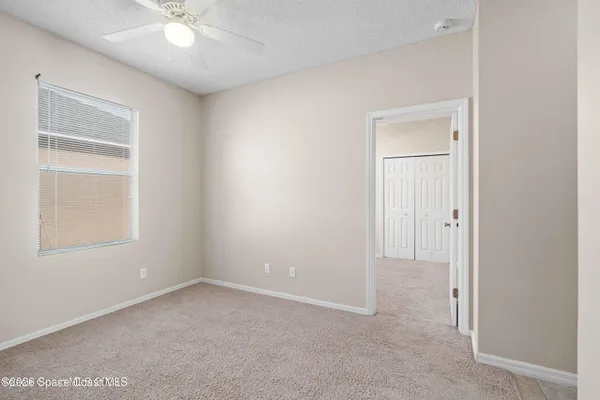 an empty room with chandelier fan and windows