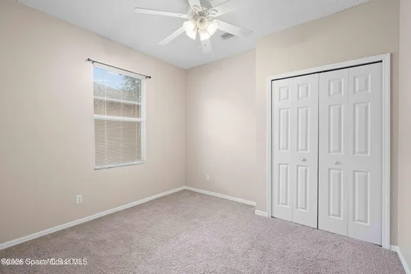 an empty room with windows and fan