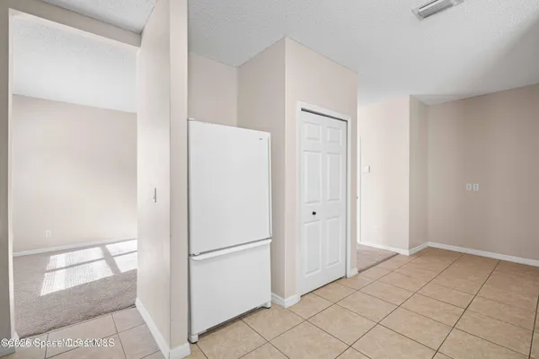 a view of a refrigerator in kitchen and an empty room