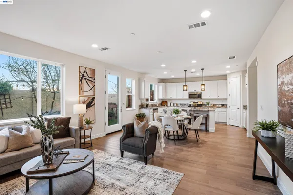 a living room with furniture kitchen view and a large window