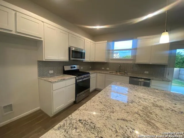 a kitchen with stainless steel appliances granite countertop a stove a sink and a microwave