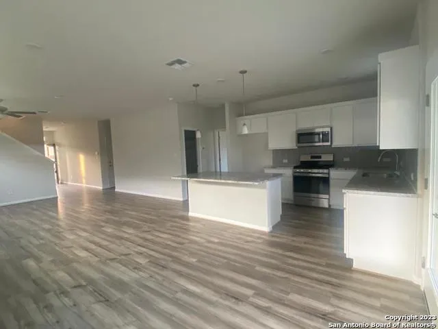 a view of kitchen with granite countertop stainless steel appliances and wooden floor