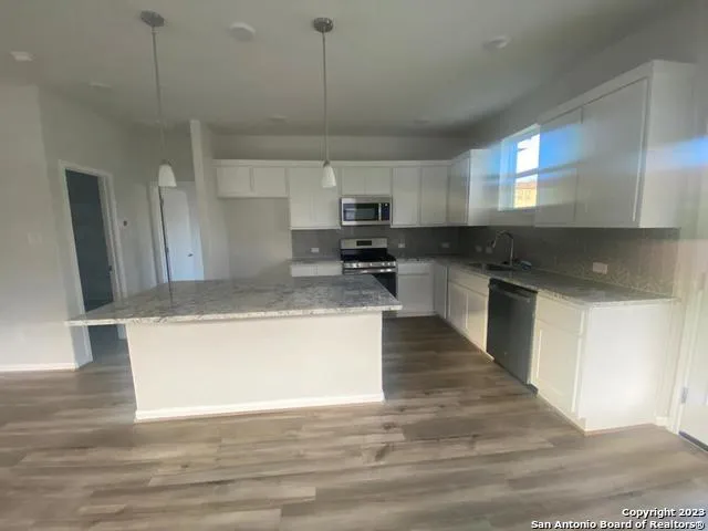 a large kitchen with stainless steel appliances granite countertop a stove a sink and a refrigerator