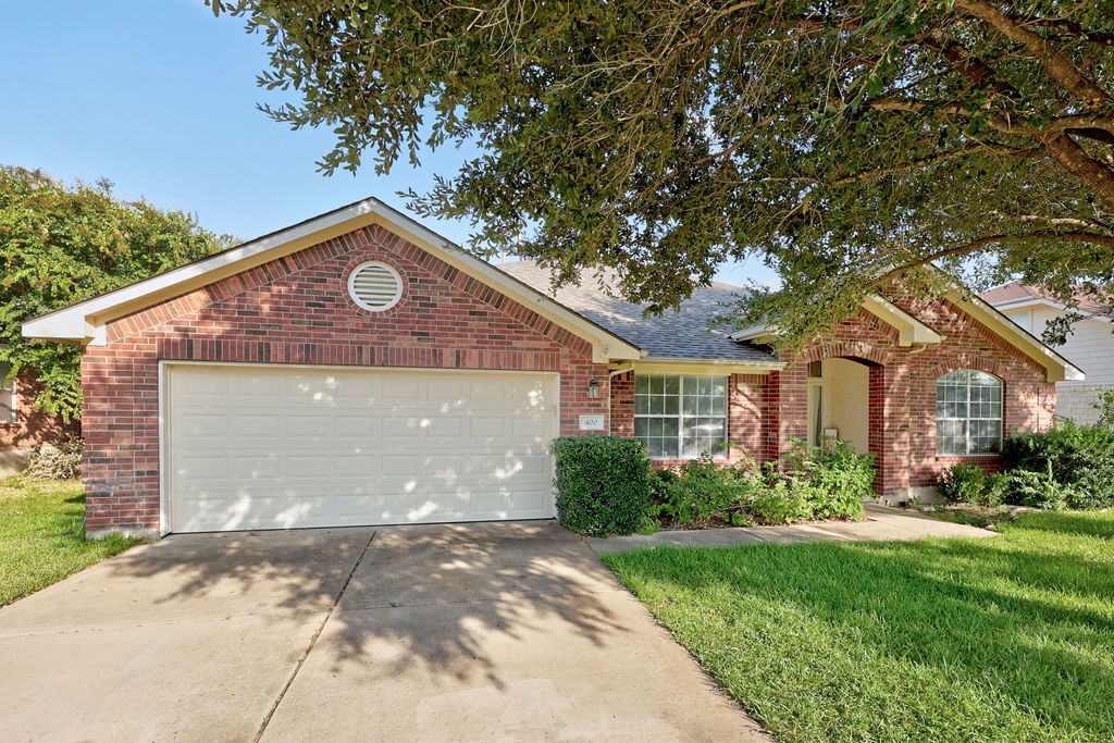 400 Ranier Lane Round Rock, TX 78665 - Photo 5 of 36 Mature shade trees frame this classic single-story brick facade featuring an attached garage.