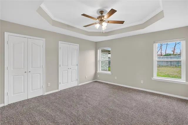 an empty room with windows and ceiling fan