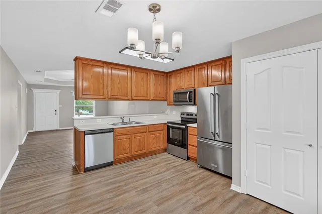 a kitchen with kitchen island granite countertop wooden floors stainless steel appliances a sink and a window