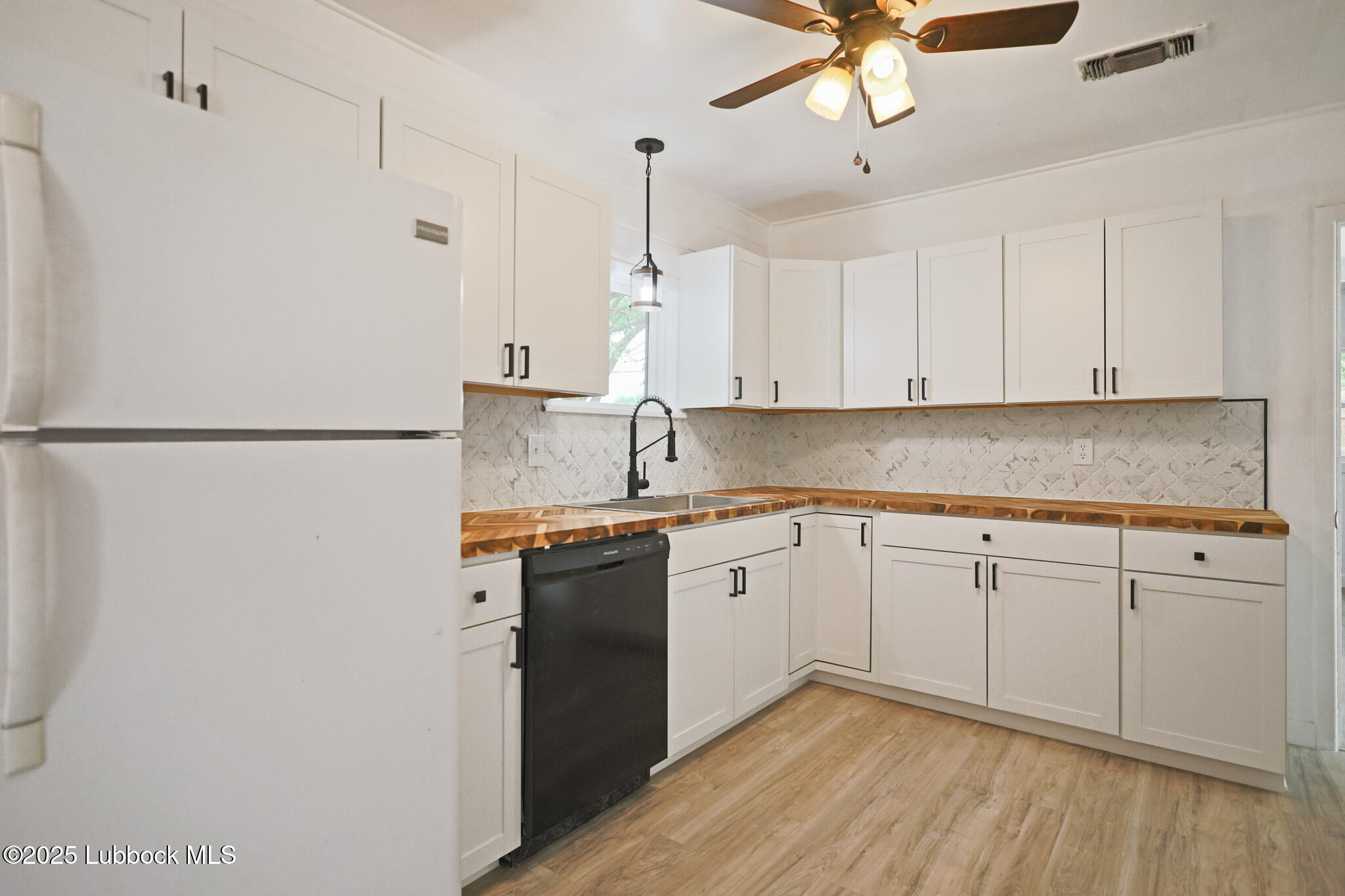 204 Chestnut Street Ropesville, TX 79358 - Photo 10 of 42 a kitchen with stainless steel appliances granite countertop a refrigerator a sink dishwasher a stove and white countertops with wooden floor