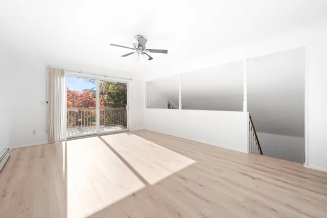 a view of empty room with wooden floor and fan