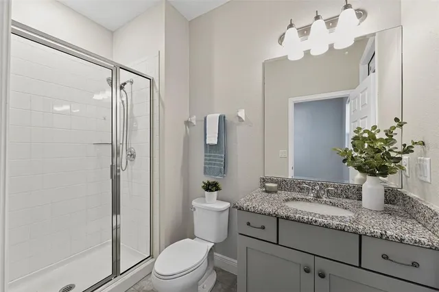a bathroom with a granite countertop sink a toilet and shower
