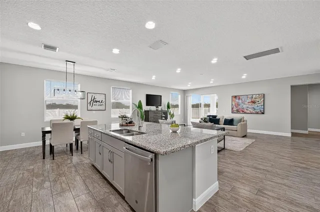 a kitchen with stainless steel appliances granite countertop a table chairs sink refrigerator and cabinets