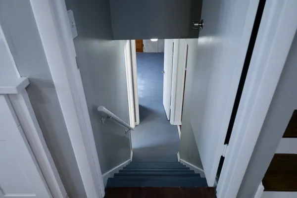 a view of staircase with white walls and refrigerator
