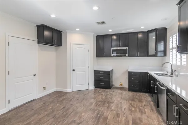a kitchen with stainless steel appliances granite countertop a sink and a stove top oven with wooden floor