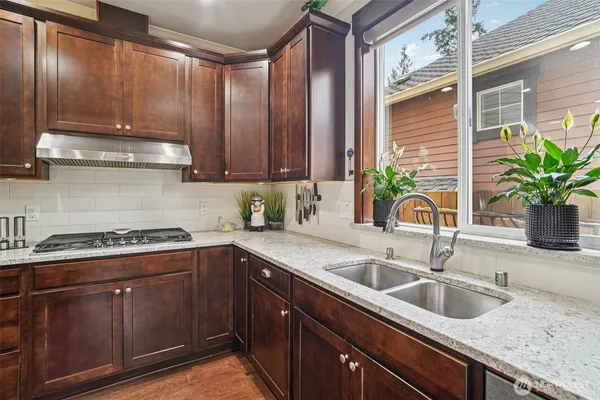 a kitchen with granite countertop a sink a stove and cabinets