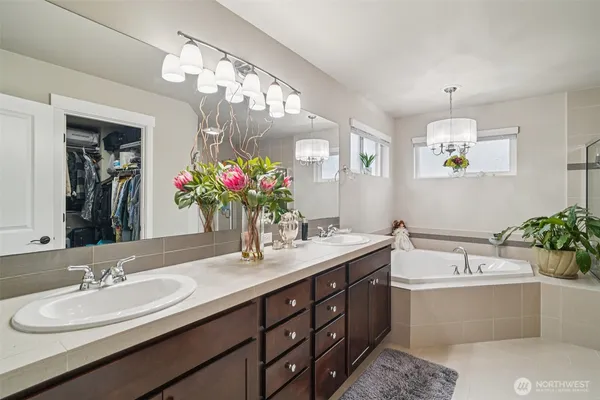 a bathroom with a tub a potted plant and a shower