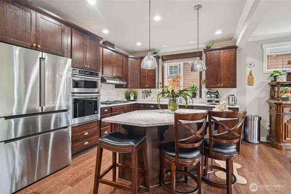 a kitchen with granite countertop a table chairs refrigerator and microwave