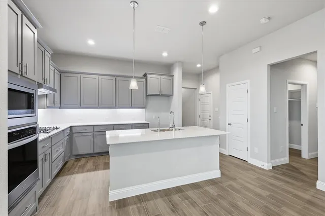 a large kitchen with stainless steel appliances kitchen island granite countertop a stove a sink and a refrigerator