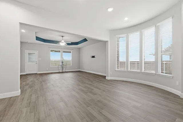a view of empty room with wooden floor and fan