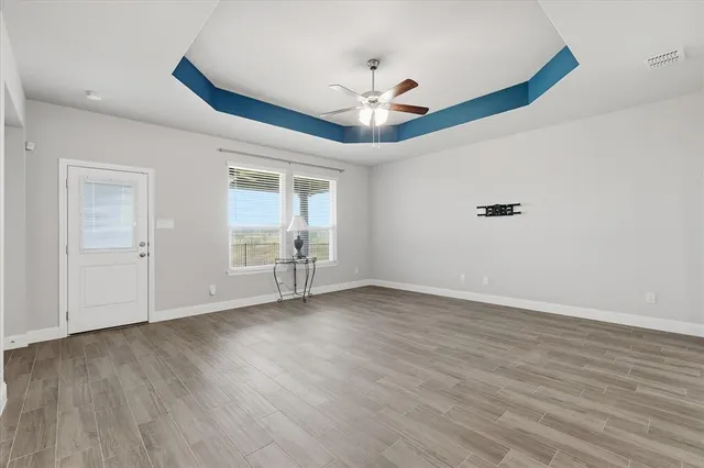 a view of an empty room with wooden floor and a ceiling fan