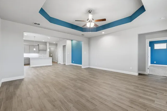 a view of an empty room with wooden floor and a ceiling fan