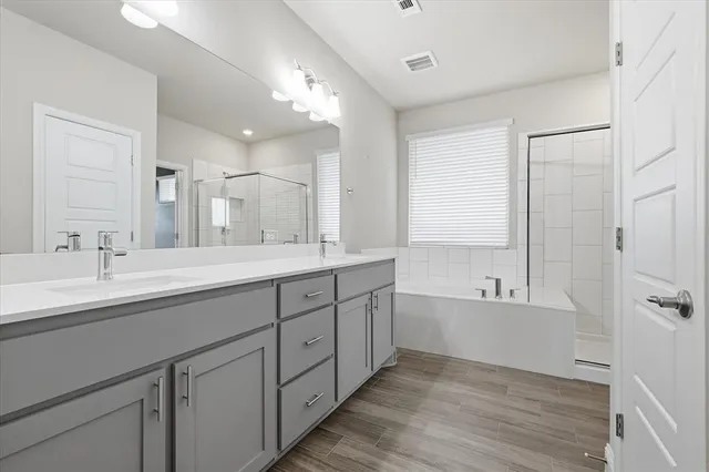 a spacious bathroom with a double vanity sink a mirror and a bathtub