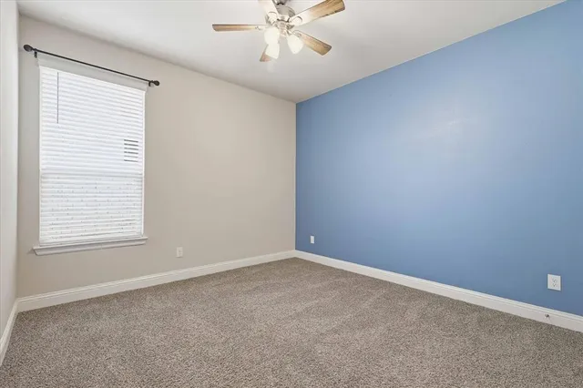 an empty room with a window and a fan