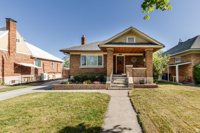Brick exterior with a south facing covered front porch featuring stone steps and column supports