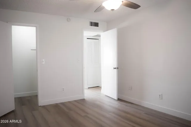 an empty room with wooden floor and fan