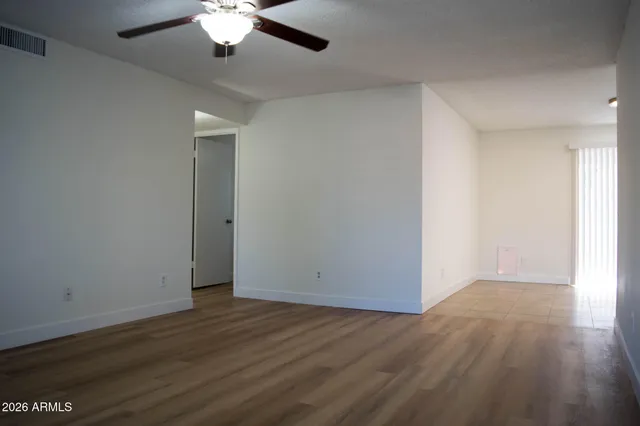 an empty room with wooden floor chandelier fan and windows