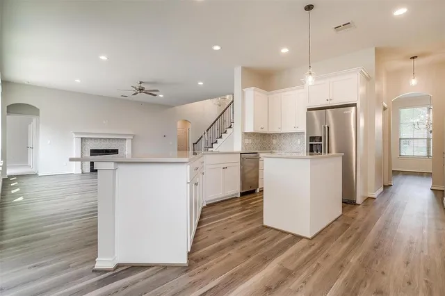 a kitchen with a refrigerator a stove top oven a sink and a wooden floor