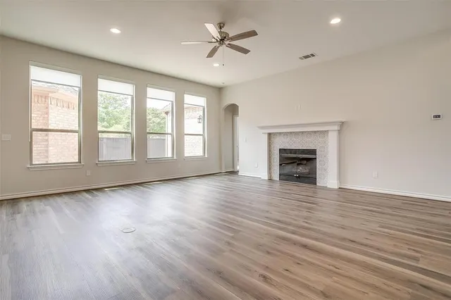 an empty room with wooden floor fireplace and windows