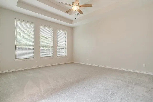 an empty room with windows and ceiling fan