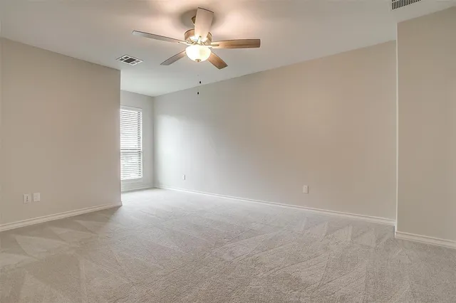 an empty room with a chandelier fan and windows