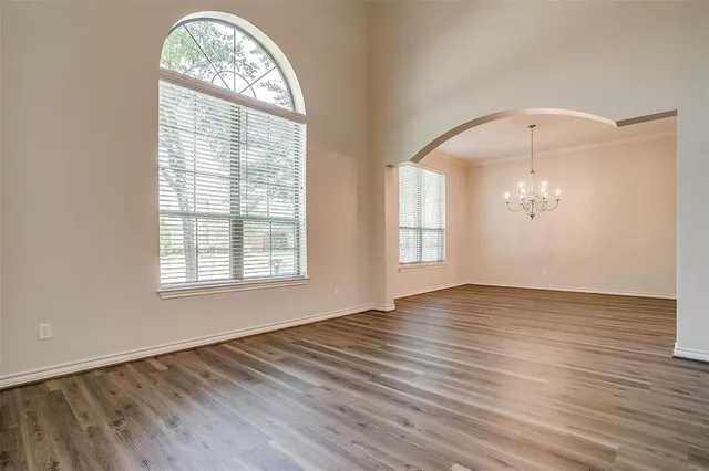 an empty room with wooden floor mirror and windows
