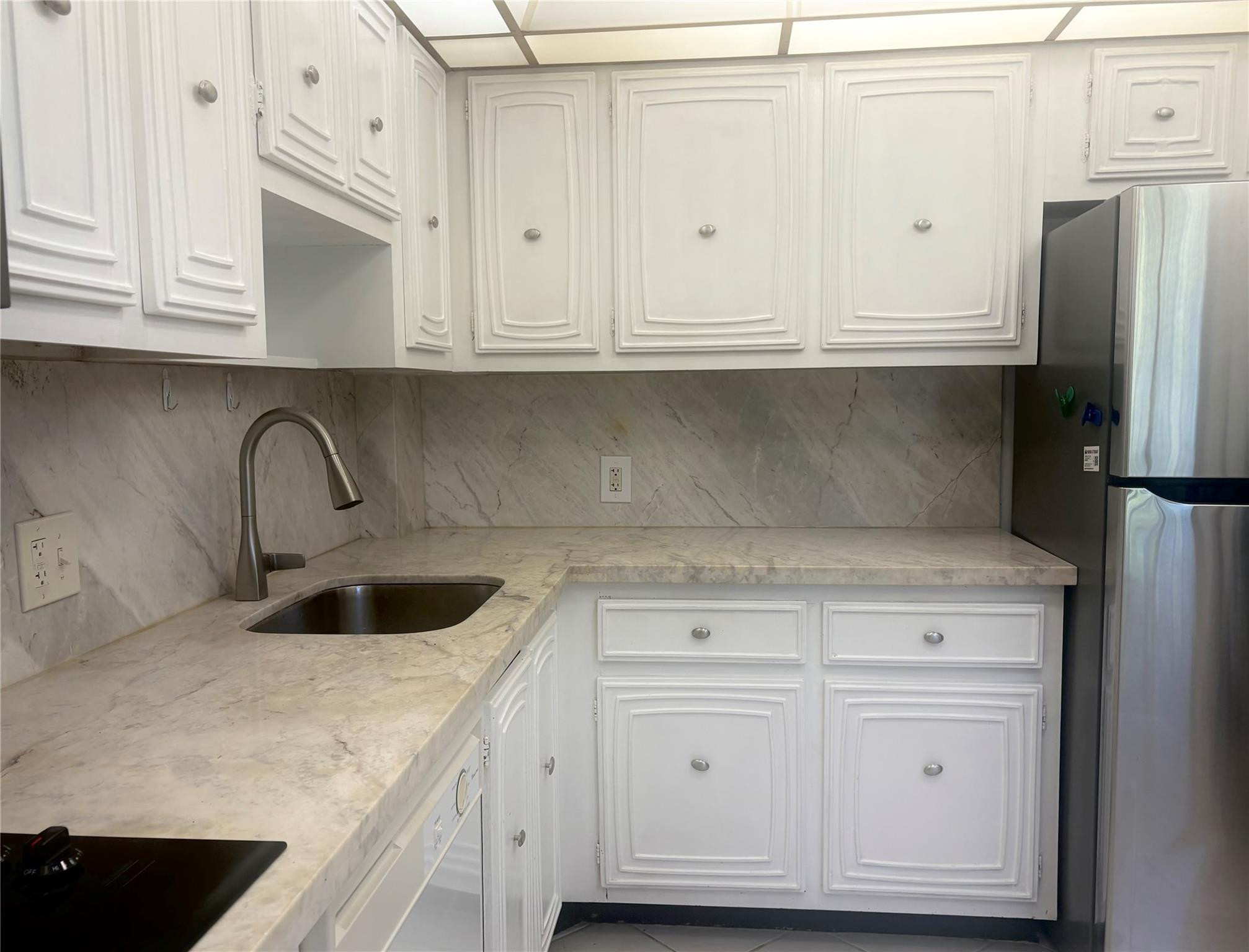 2601 South Course Drive, Unit 406 Pompano Beach, FL 33069 - Photo 2 of 15 a kitchen with white cabinets and a sink