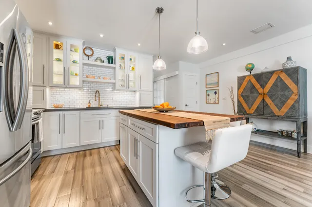 a kitchen with stainless steel appliances granite countertop a sink a stove a refrigerator and island with wooden floor