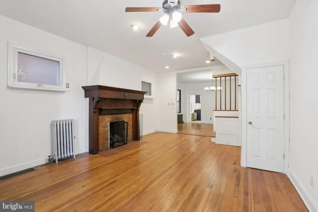 a view of an empty room with wooden floor and a fireplace