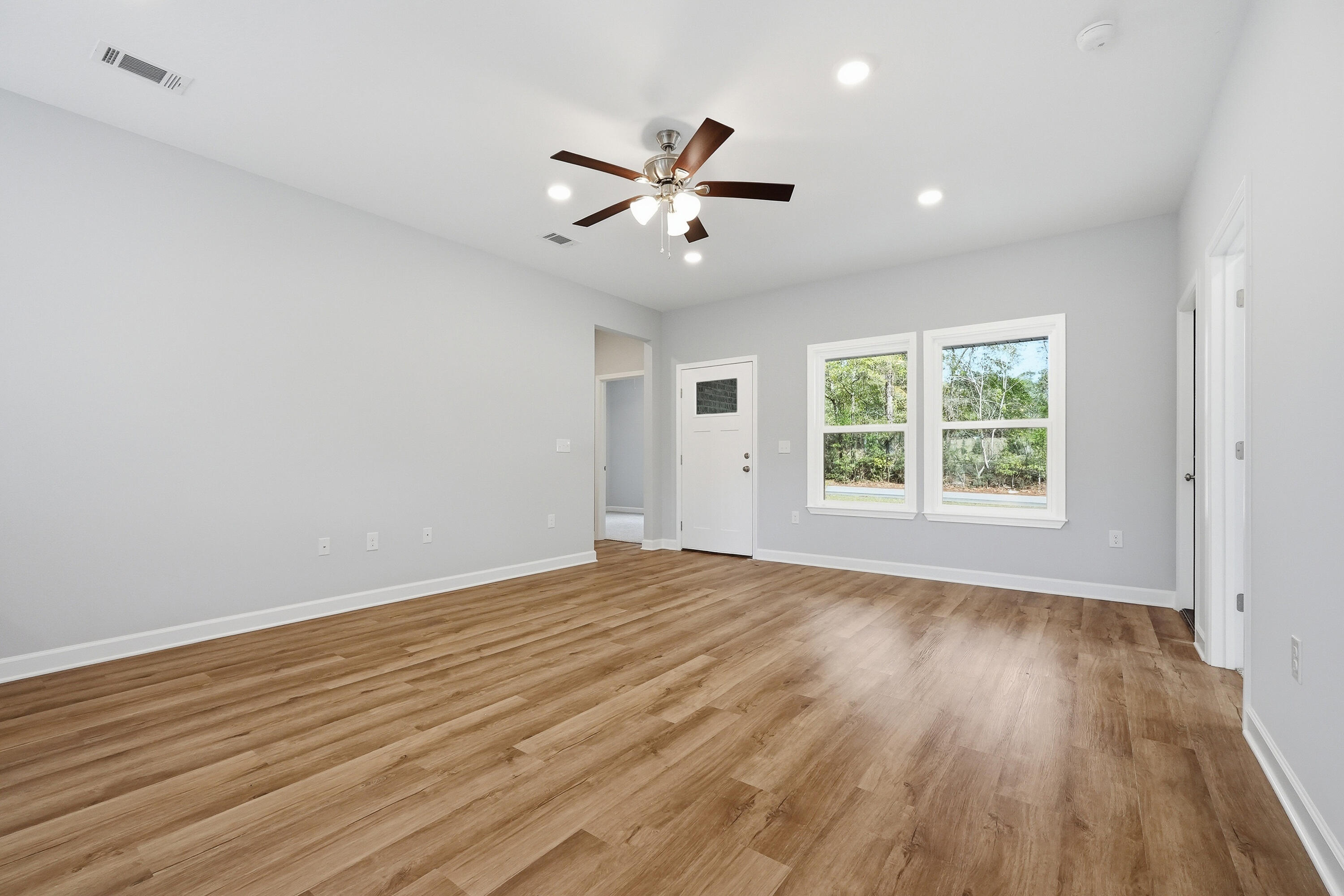 2588 Kingston Road Crestview, FL 32536 - Photo 5 of 23 an empty room with wooden floor a ceiling fan and windows