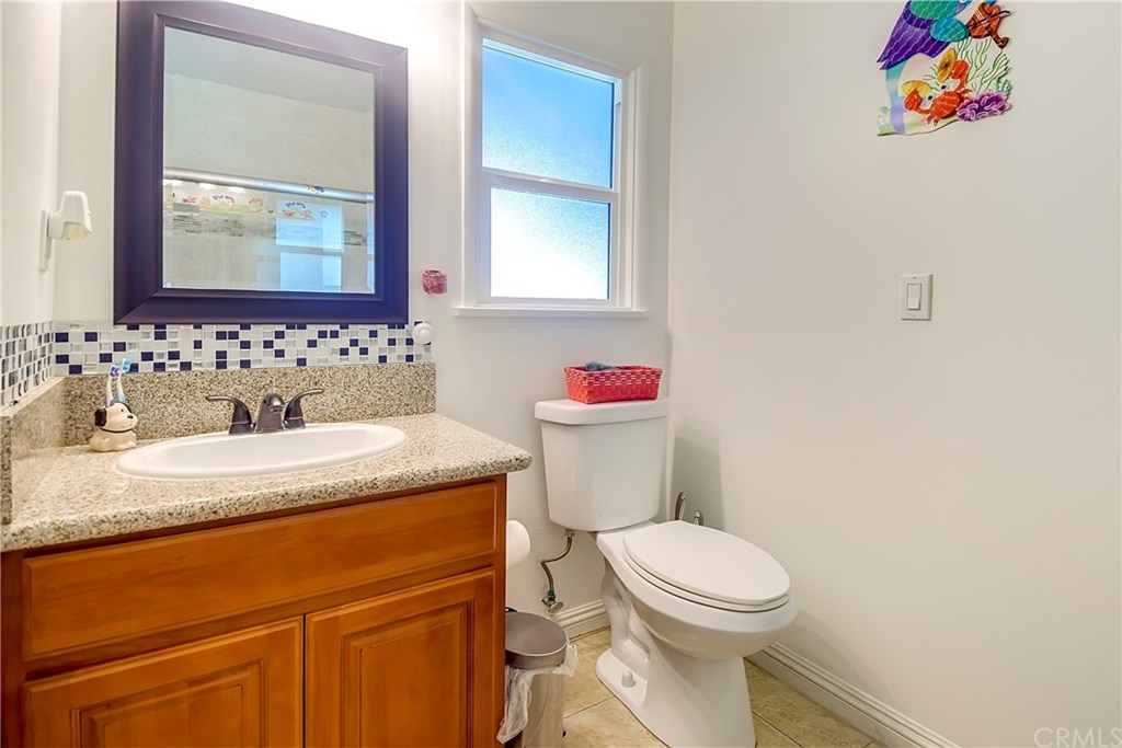 7863 Lyndora Street Downey, CA 90242 - Photo 9 of 27 a bathroom with a granite countertop toilet sink and mirror