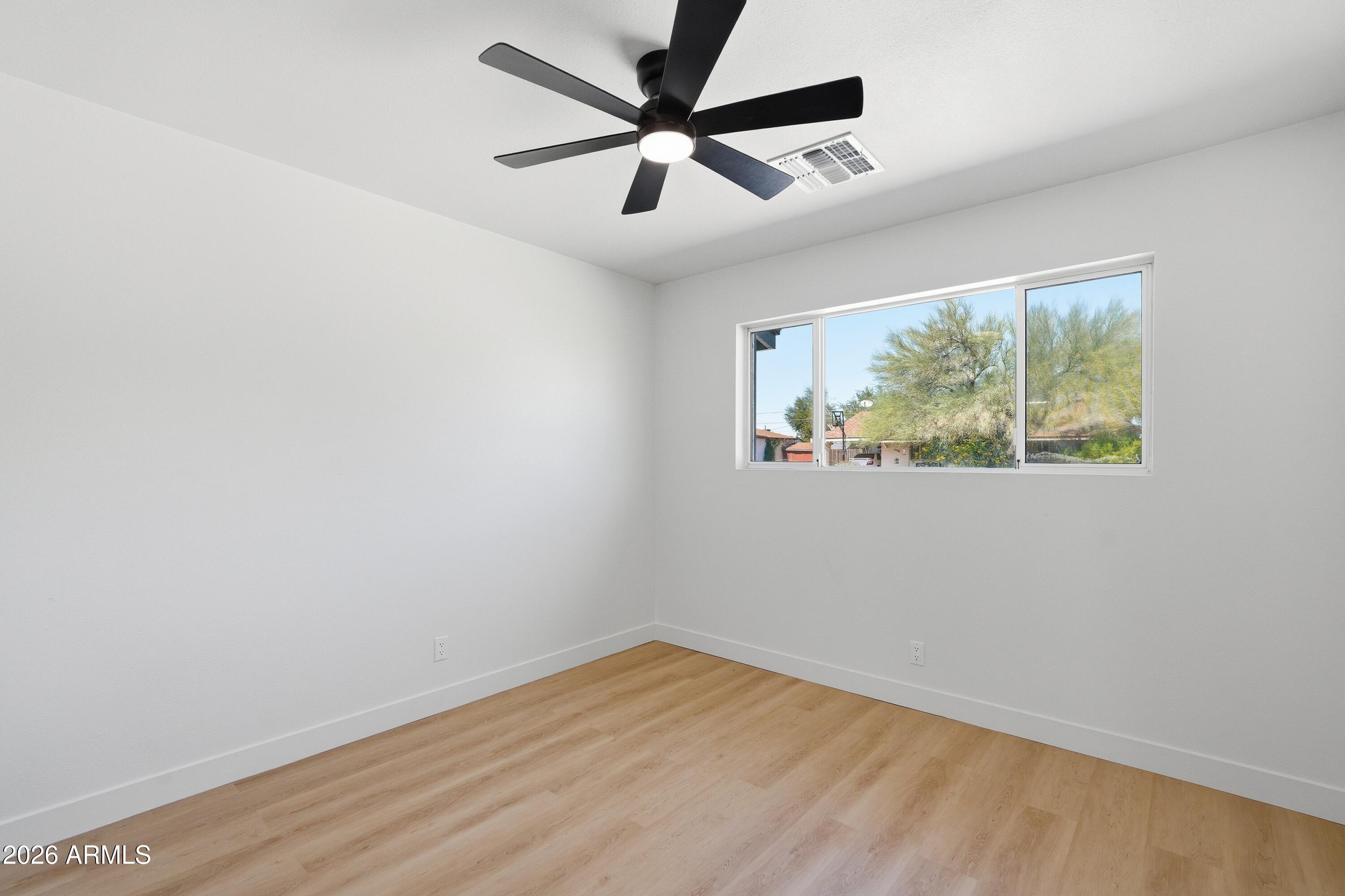 3327 West Wethersfield Road Phoenix, AZ 85029 - Photo 20 of 30 an empty room with wooden floor and windows