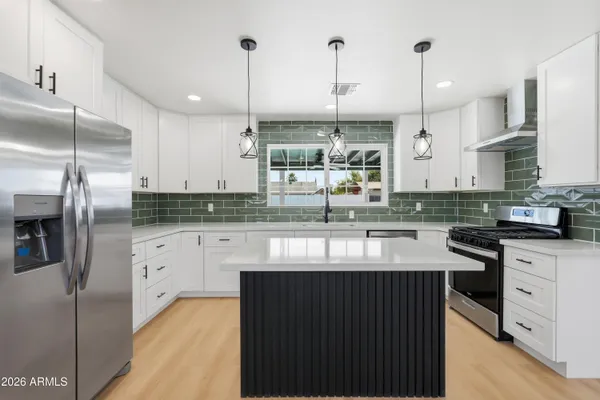a kitchen with stainless steel appliances granite countertop a sink a stove and a refrigerator