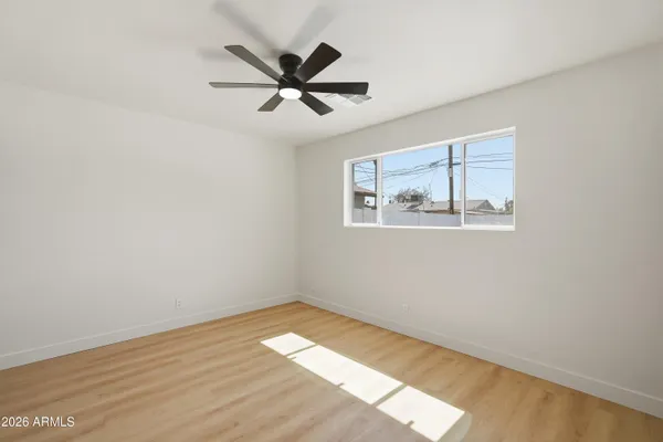 a view of empty room with wooden floor and fan