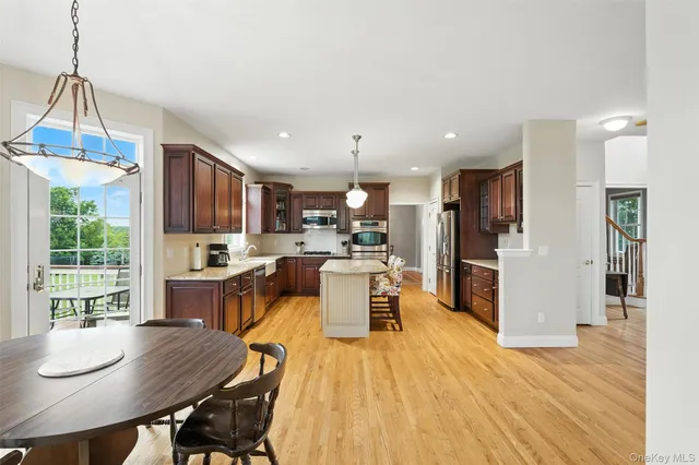 a large kitchen with stainless steel appliances granite countertop a stove a sink dishwasher a microwave oven and a dining table with wooden floor